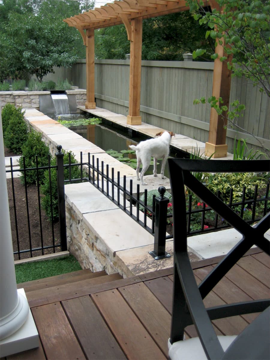 Wooden pergola over a long water channel with a waterfall spout and lily pads